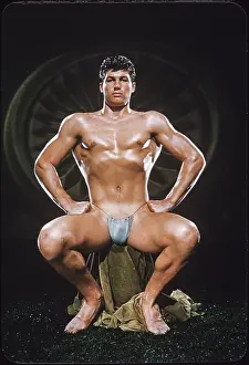 Nude Prints: Seated Handsome Bodybuilder in Blue Posing Pouch c.1950