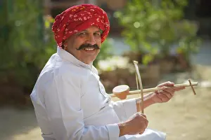 Instrument Prints: A SENIOR ADULT VILLAGER LOOKING AT CAMERA WHILE HOLDING TRADITIONAL MUSICAL INSTRUMENT