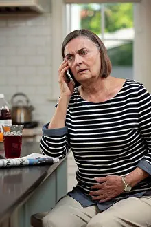 Newspaper Prints: Senior Caucasian woman in her kitchen describing her abdominal pain to doctor on the phone