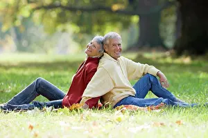 Older Adults Prints: Senior couple sitting back to back in a park