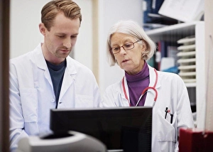 Mid Adultman Prints: Senior female doctor with male colleague using computer in examination room