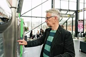 Technologies Prints: Senior male commuter using kiosk at railroad station