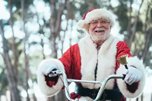 Bicycle Prints: From below senior man in costume of Santa Claus sitting on cycle