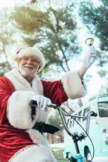 Bicycle Prints: From below senior man in costume of Santa Claus sitting on cycle