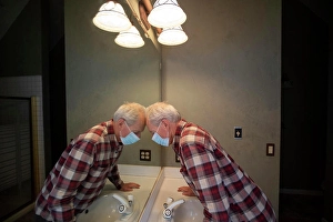 One Senior Man Only Prints: Senior man in Covid protective mask leaning head on mirror in bathroom