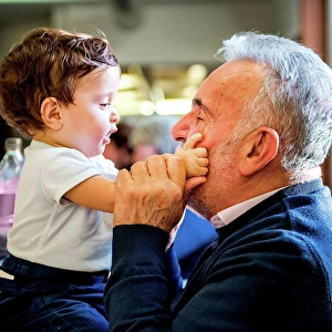 Cafeteria Prints: Senior man face to face with baby grandson in cafe