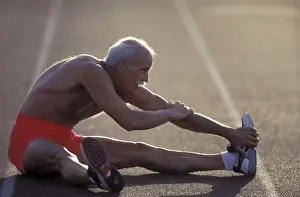 Bald Prints: Senior shirtless man doing stretching sit-ups on an outdoor track