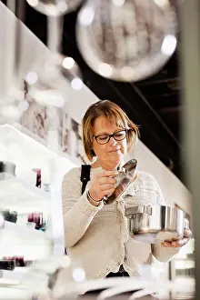 Vertically Prints: Senior woman buying cookware in shopping mall