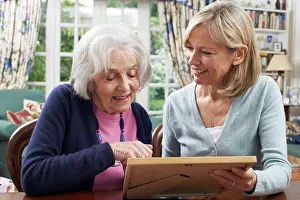 Social Issue Prints: Senior Woman Looks At Photo In Frame With Mature Female Neighbor