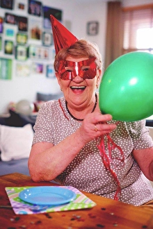 Upper Body Prints: Senior woman waving balloons at birthday party