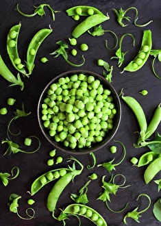 Flat Lay Prints: Shelled green peas and pea pods on a black background