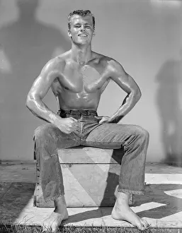 Bodybuilder Prints: Shirtless Young Bodybuilder Seated in Jeans Flexes Lats Outdoors c.1959