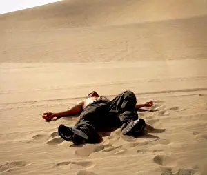 Oneperson Only Prints: Shirtless young man lying on his back in a dandy desert