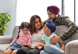 Father Prints: A SIKH FAMILY LAUGHING TOGETHER AND SPENDING TIME TOGETHER SITTING ON SOFA