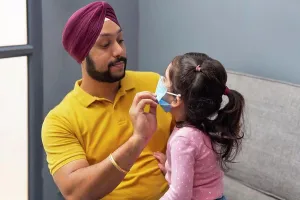 Sikh Prints: A SIKH MAN HELPING HIS LITTLE DAUGHTER TO WEAR MASK BEFORE GOING OUT
