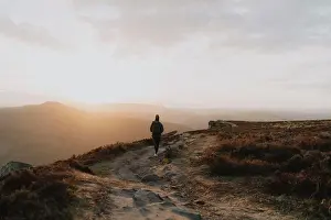 Silhouetted woman watching sunset from tranquil cliff, Bamford Edge, Derbyshire, England
