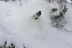 A skier descends a snowy slope through deep powder on a beautiful day in Kirkwood, California