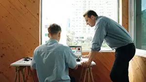Electronic Prints: Skilled teacher looking at young highschool student fixing car model while laptop screen display coding engineering