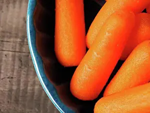 Close View Prints: Small baby carrots in a rustic blue ceramic bowl, close up shot