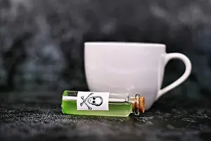 Cork Prints: Small vial with cork and green liquid and poison skull label next to tea cup on dark background