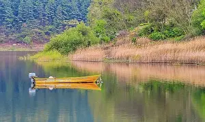 South Korea Prints: Small yellow metal fishing boat with small engine mount floating peacefully on a lake in South Korea