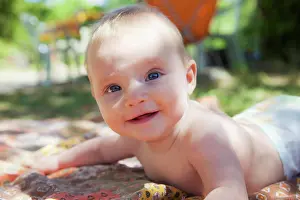 Lying Down Prints: Smiling baby raised on his arms in the garden