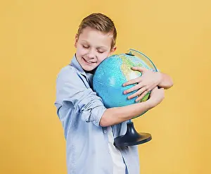 Worlds Prints: Smiling boy embracing globe hand against yellow backdrop