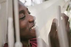 Using Phone Prints: Smiling boy using mobile phone while relaxing on hammock