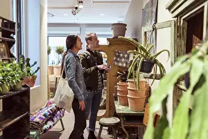 Asian And Indian Ethnicities Prints: Smiling couple looking at wall decor while shopping in boutique