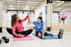 Disability Prints: Smiling disabled athlete giving high-five to friend in gym