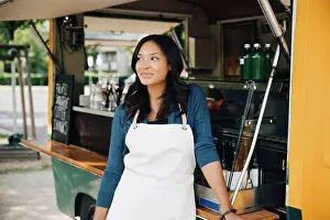 Self Employed Prints: Smiling female owner looking away while standing against food truck