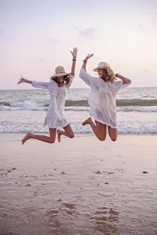 Traveling Prints: Smiling girlfriends in summer clothes barefoot in water on beach