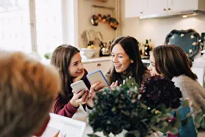 Using Phone Prints: Smiling girls using mobile phone while sitting at table in room