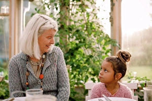 Frgbild Prints: Smiling grandmother looking at granddaughter while having lunch