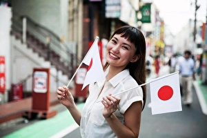 Retail Business Prints: Smiling Japanese woman with long brown hair wearing white short-sleeved blouse standing in a street