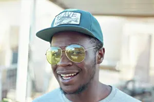 Fashion Prints: A smiling man wearing reflective sunglasses and a black cap with a patch