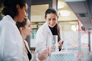 Instruction Prints: Smiling mature teacher with young female students learning chemistry at laboratory