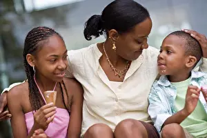 30 To 35 Years Prints: Smiling mother sitting with her arm around her daughter and son