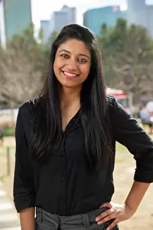 Lighthearted Prints: Smiling portrait of young ethnic woman with long black hair standing in park wearing black blouse