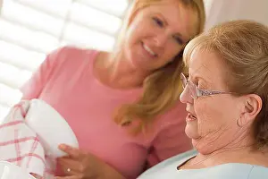 Conversations Prints: Smiling senior adult woman and young daughter talking at sink in kitchen