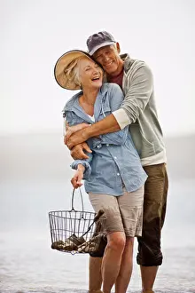 Baby Boomer Prints: Smiling senior couple wading on a beach at low tide