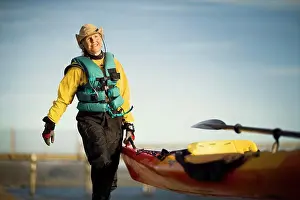 Jackets Prints: Smiling senior woman carrying the end of a kayak in the sunshine