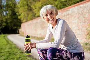 Best Prints: Smiling sportive senior woman holding bottle in park