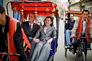 30 To 35 Years Prints: Smiling tourists riding in pedicabs along a city street