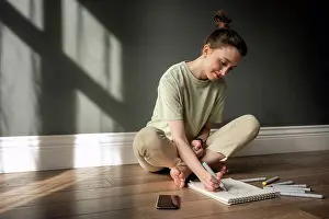 Flooring Prints: Smiling woman drawing on note pad while sitting on floor