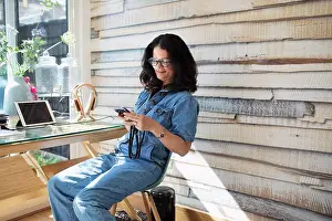 Home Office Prints: Smiling woman using smart phone in home office