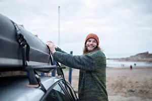 Hood Prints: Smiling young man fastening canoe onto car at beach