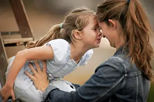 30 To 35 Years Prints: Smiling young mother holds her little girl who is sitting on a ladder