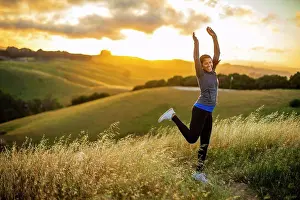 20 To 25 Years Prints: Smiling young woman jumps for joy in the countryside at sunset