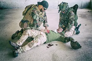 Injured Prints: Soldiers giving emergency care to a wounded comrade lying on the floor, screaming in pain